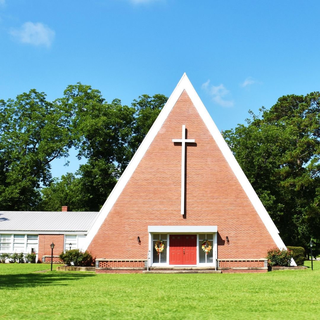 A front view of a Christian church built with an A-frame style in brick with a large white cross over the door by Scherrer Construction in Wisconsin. 